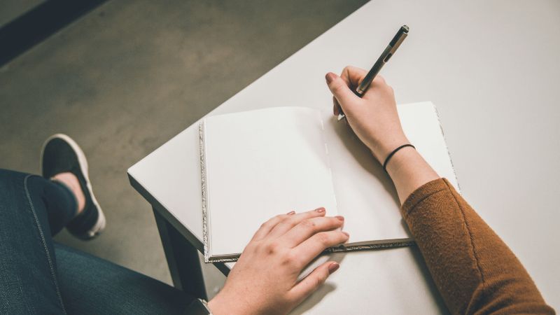 Uma pessoa começando a escrever em um caderno representando o exercício prático.